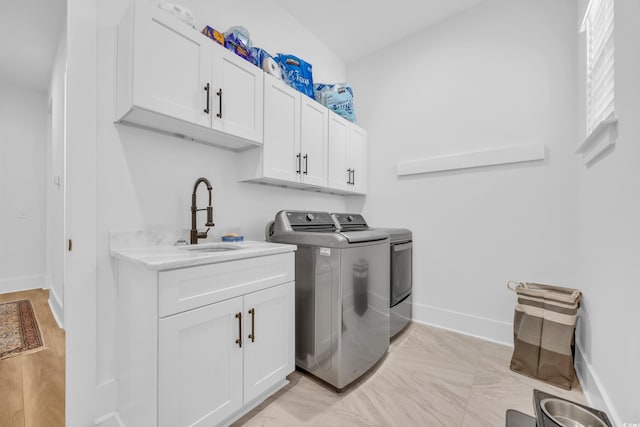 laundry area featuring washer and clothes dryer, cabinet space, baseboards, and a sink