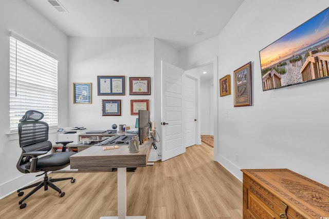 home office featuring light wood finished floors, visible vents, and baseboards