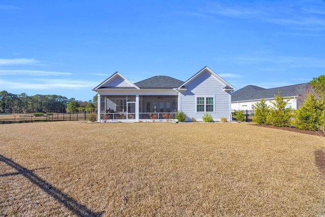 rear view of house featuring fence, a lawn, and a sunroom