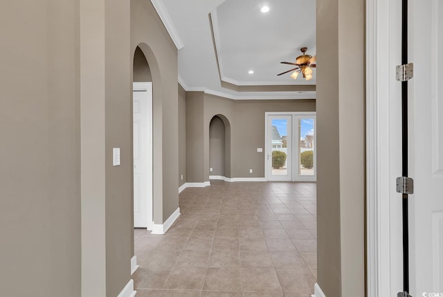 corridor featuring arched walkways, crown molding, recessed lighting, baseboards, and light tile patterned floors