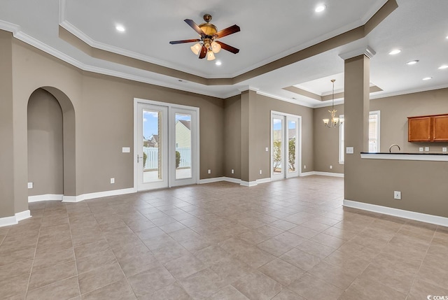 unfurnished living room featuring a tray ceiling, ceiling fan, a chandelier, crown molding, and light tile patterned floors