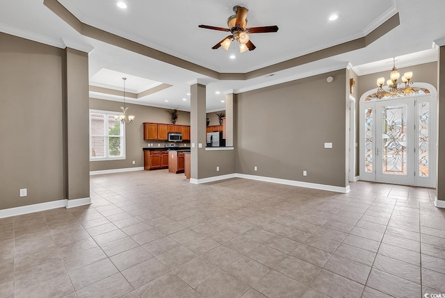 unfurnished living room with ceiling fan with notable chandelier, a raised ceiling, baseboards, and ornamental molding