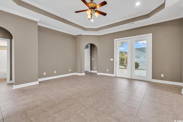 empty room featuring arched walkways, a raised ceiling, a ceiling fan, light tile patterned floors, and ornamental molding