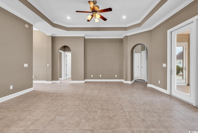 spare room featuring a ceiling fan, baseboards, arched walkways, ornamental molding, and a raised ceiling