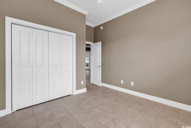 unfurnished bedroom with crown molding, light tile patterned floors, baseboards, a closet, and ceiling fan