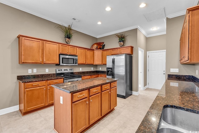 kitchen with stainless steel appliances, crown molding, dark stone counters, brown cabinetry, and a center island