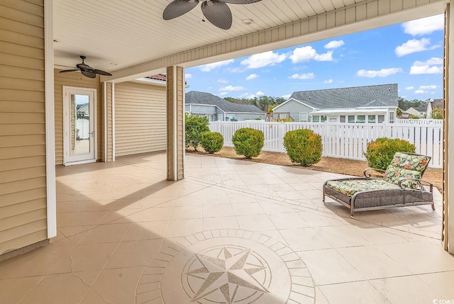 view of patio with a ceiling fan, fence, and a residential view
