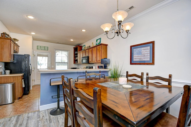 dining area featuring visible vents, light wood-style flooring, recessed lighting, a textured ceiling, and a notable chandelier