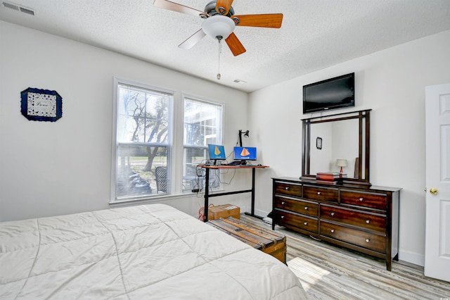 bedroom featuring wood finished floors, baseboards, visible vents, ceiling fan, and a textured ceiling