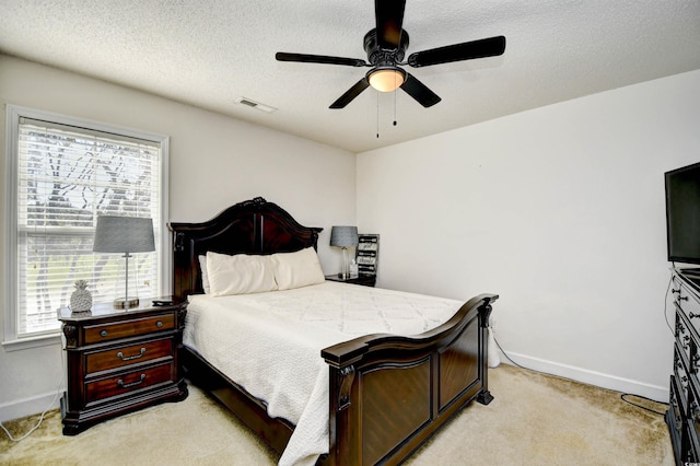 bedroom with visible vents, baseboards, light colored carpet, and a textured ceiling