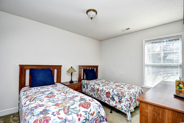 bedroom featuring visible vents, a textured ceiling, and carpet