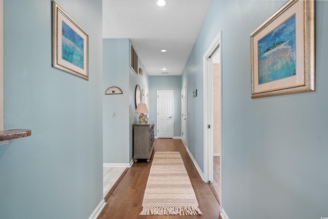 hall featuring recessed lighting, baseboards, and wood finished floors