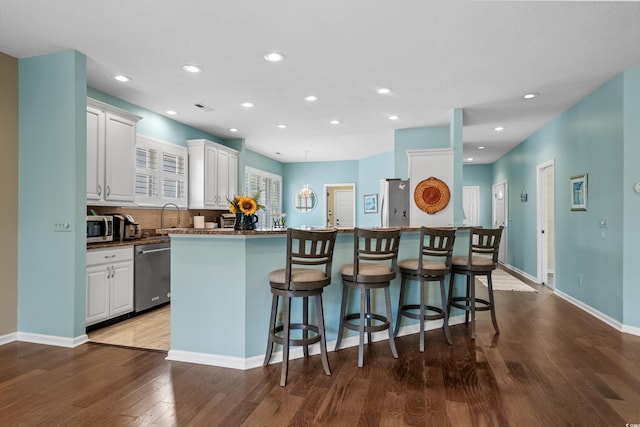 kitchen with a kitchen bar, white cabinetry, and appliances with stainless steel finishes