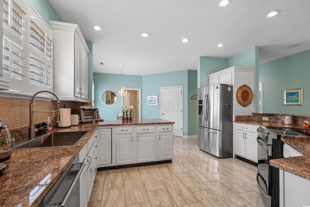 kitchen featuring white cabinetry, a peninsula, appliances with stainless steel finishes, and a sink