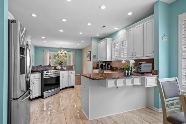 kitchen featuring visible vents, a peninsula, white cabinets, stainless steel appliances, and a sink