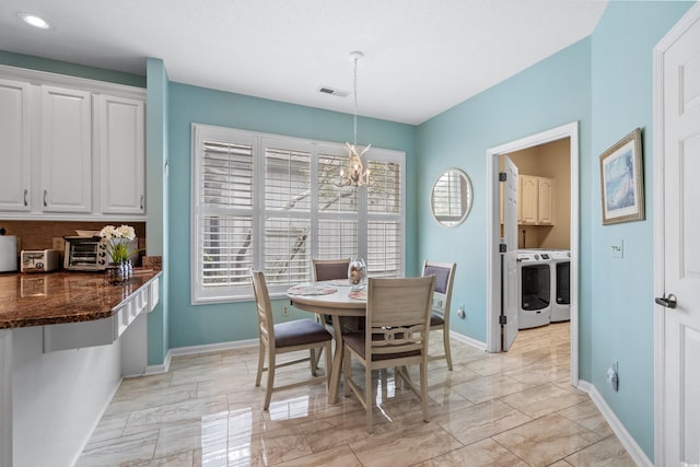 dining room with visible vents, washing machine and dryer, an inviting chandelier, and baseboards