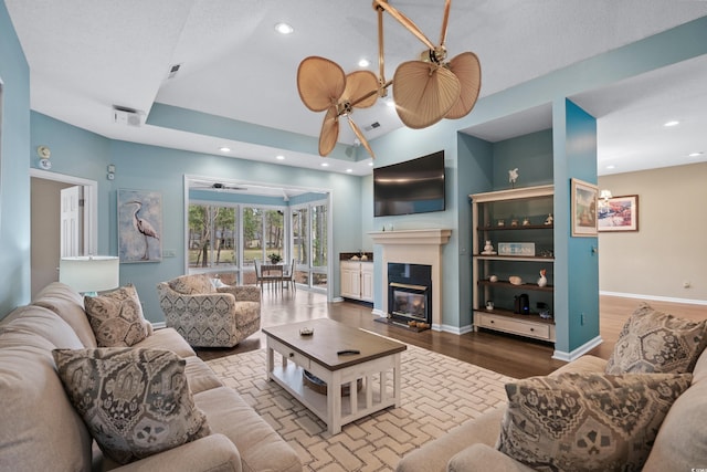 living room featuring baseboards, ceiling fan, recessed lighting, wood finished floors, and a glass covered fireplace