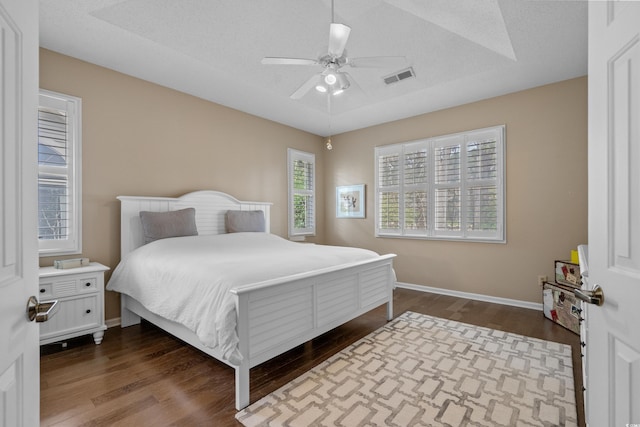 bedroom with visible vents, a ceiling fan, baseboards, and dark wood-style flooring