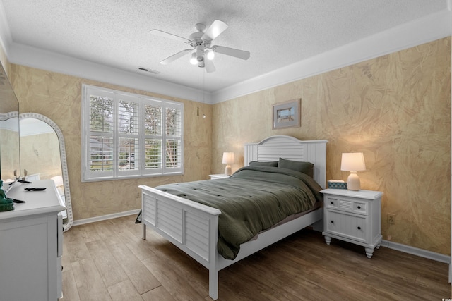 bedroom featuring visible vents, baseboards, light wood-style floors, and a textured ceiling