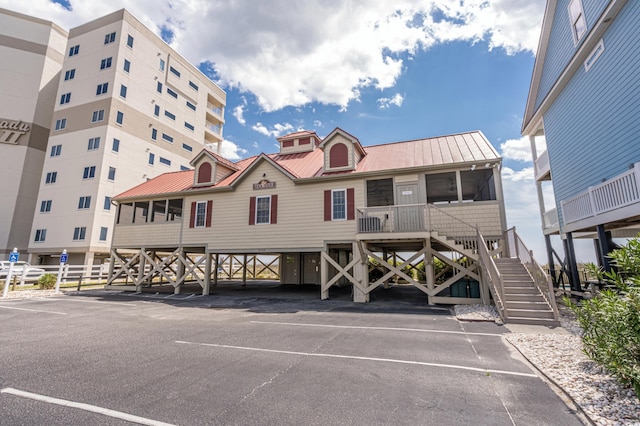 view of property with stairs and covered and uncovered parking