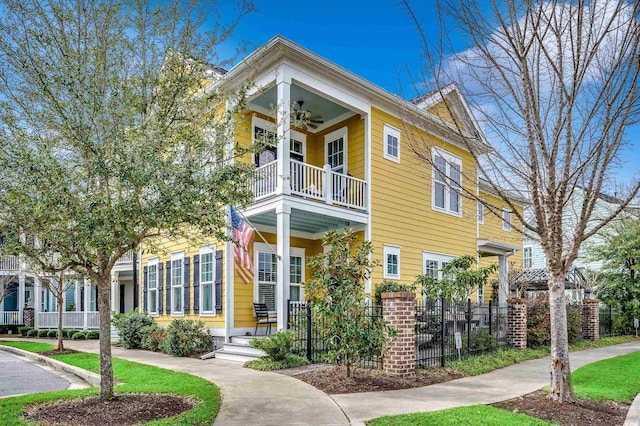 view of front of house with a balcony, ceiling fan, and fence