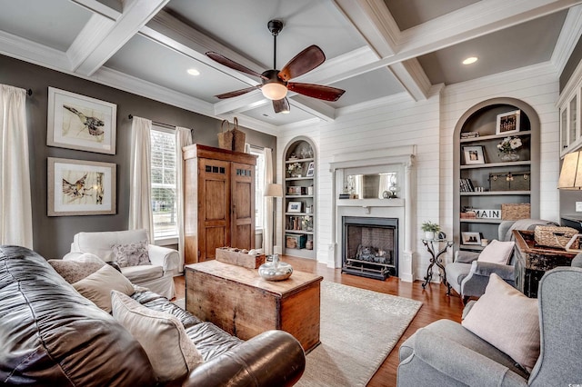 living area featuring built in features, wood finished floors, coffered ceiling, beam ceiling, and a fireplace