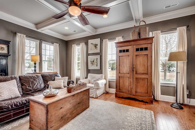 living room with a wealth of natural light, visible vents, coffered ceiling, and light wood-type flooring