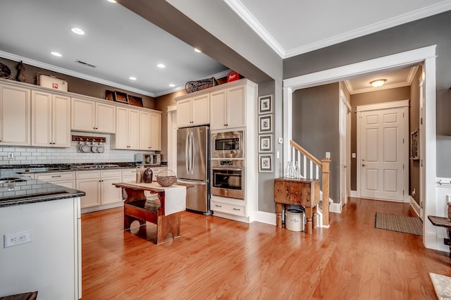 kitchen featuring white cabinetry, light wood finished floors, appliances with stainless steel finishes, and ornamental molding