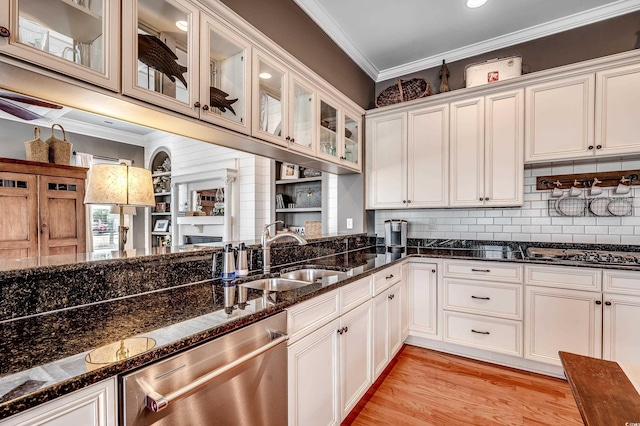 kitchen with dark stone countertops, a sink, ornamental molding, stainless steel appliances, and white cabinetry