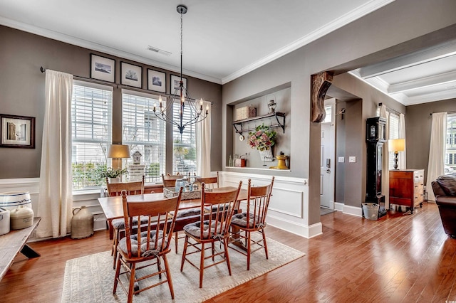 dining room with visible vents, wood finished floors, an inviting chandelier, wainscoting, and crown molding