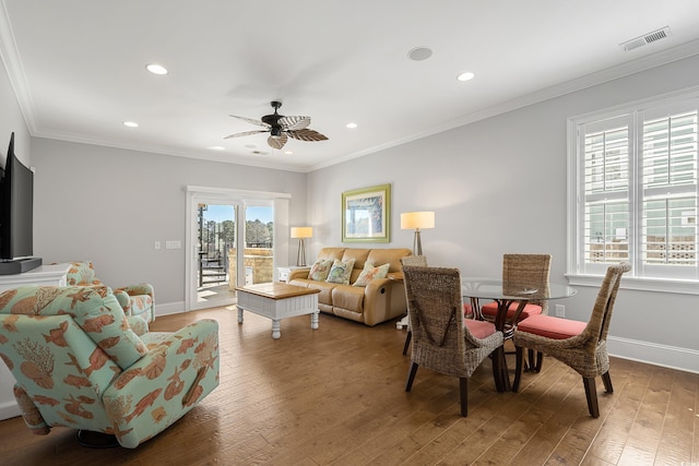 living room with visible vents, baseboards, ceiling fan, ornamental molding, and wood finished floors