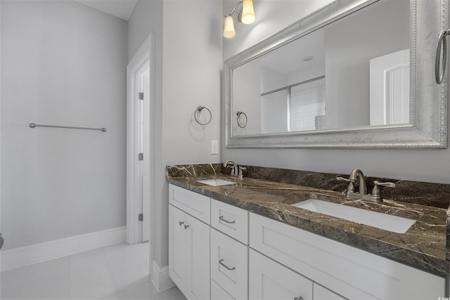 full bath with tile patterned floors, double vanity, baseboards, and a sink