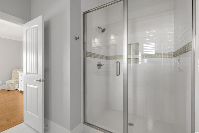 bathroom with wood finished floors, baseboards, and a stall shower