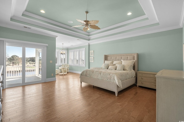 bedroom with access to exterior, visible vents, crown molding, hardwood / wood-style floors, and a raised ceiling