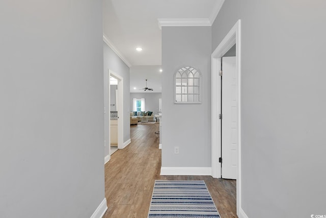 hallway with light wood finished floors, recessed lighting, baseboards, and ornamental molding