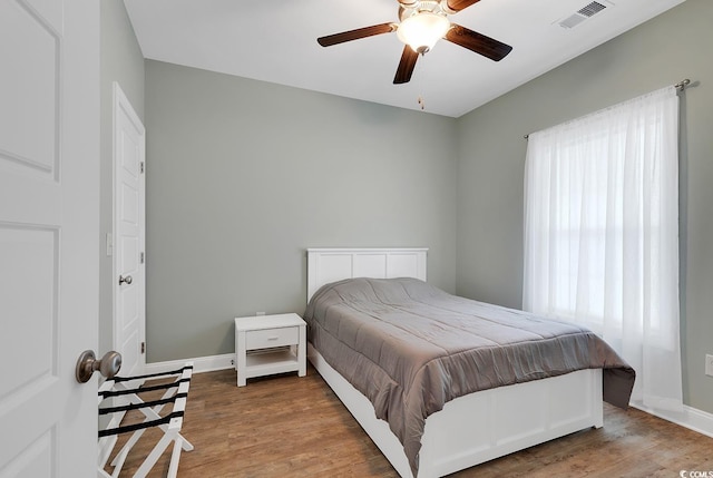 bedroom featuring visible vents, baseboards, wood finished floors, and a ceiling fan