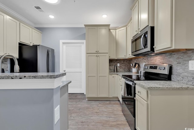 kitchen featuring light stone counters, visible vents, light wood-style flooring, stainless steel appliances, and decorative backsplash