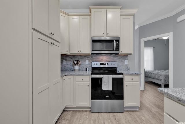 kitchen featuring light wood-style flooring, ornamental molding, backsplash, appliances with stainless steel finishes, and light stone countertops