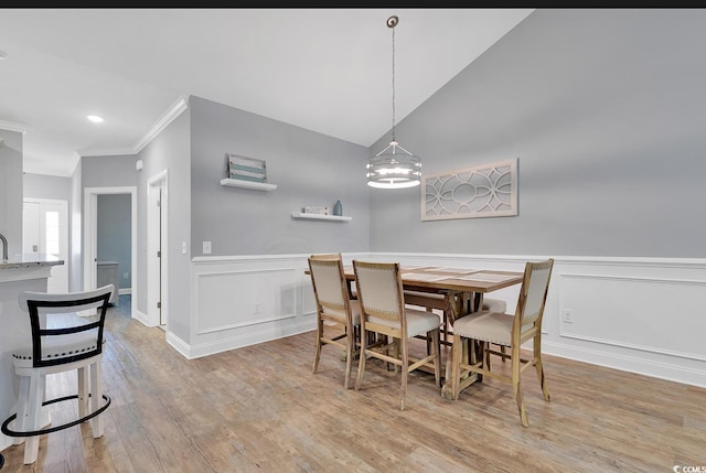 dining room with wood finished floors, wainscoting, and ornamental molding