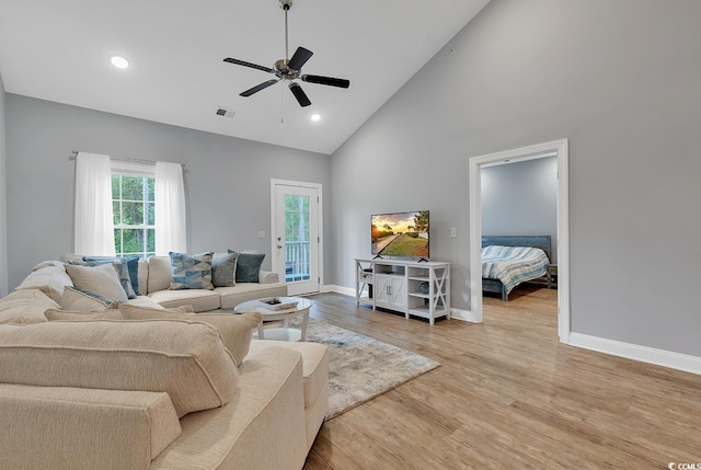 living room with baseboards, visible vents, light wood finished floors, high vaulted ceiling, and ceiling fan