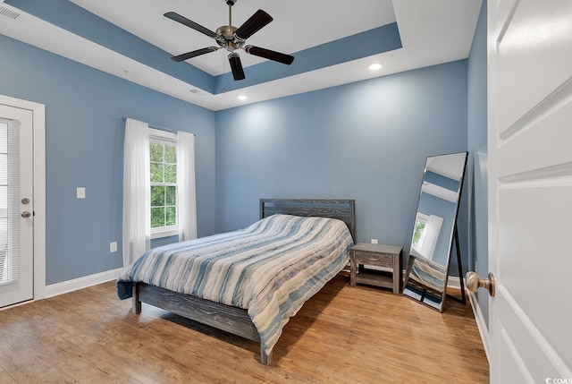 bedroom featuring recessed lighting, a raised ceiling, baseboards, and wood finished floors