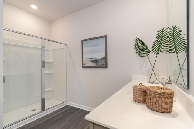 bathroom featuring wood finished floors, a stall shower, vanity, and baseboards