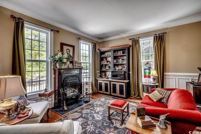 sitting room featuring a wealth of natural light, wood finished floors, and ornamental molding