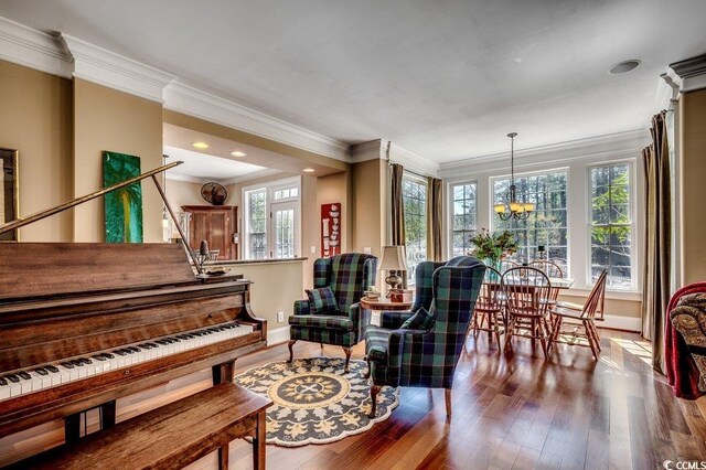 sitting room with baseboards, a chandelier, stairs, ornamental molding, and wood finished floors