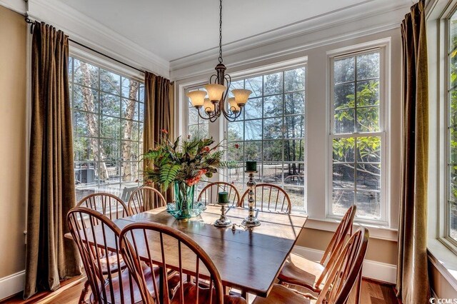 dining area featuring baseboards, crown molding, an inviting chandelier, and wood finished floors