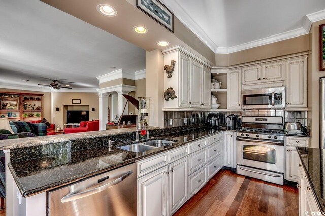 kitchen featuring dark wood-style flooring, ornamental molding, stainless steel appliances, and a sink