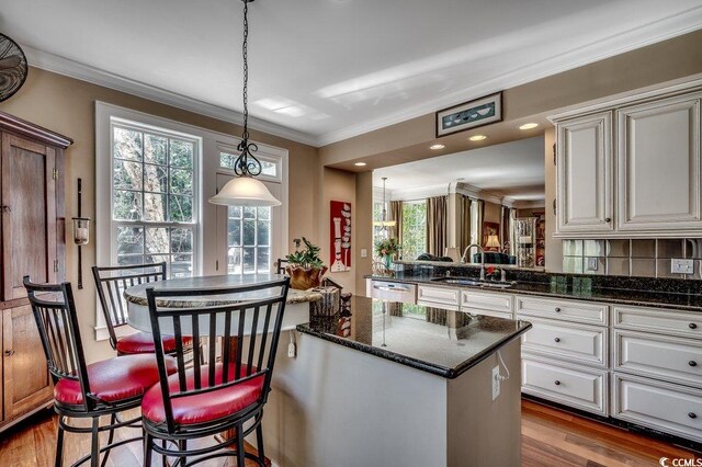 kitchen featuring a sink, a center island, crown molding, dark wood-style floors, and stainless steel dishwasher