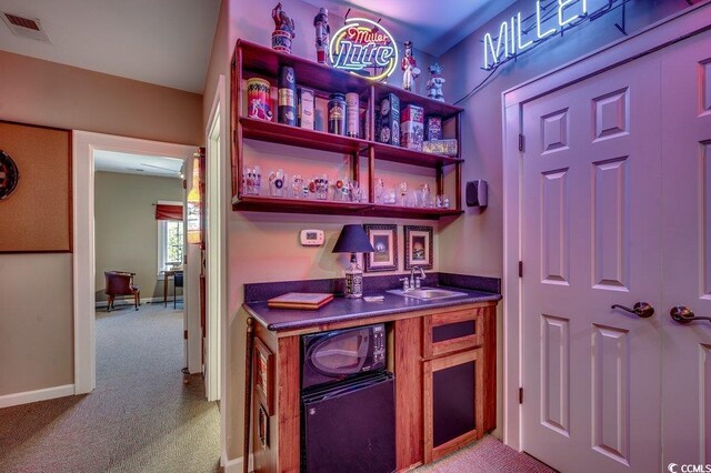 bar with visible vents, a sink, indoor wet bar, black microwave, and light colored carpet