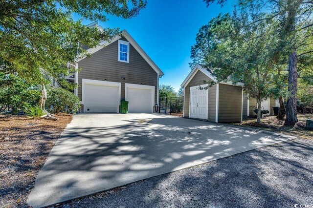 garage featuring concrete driveway and a shed