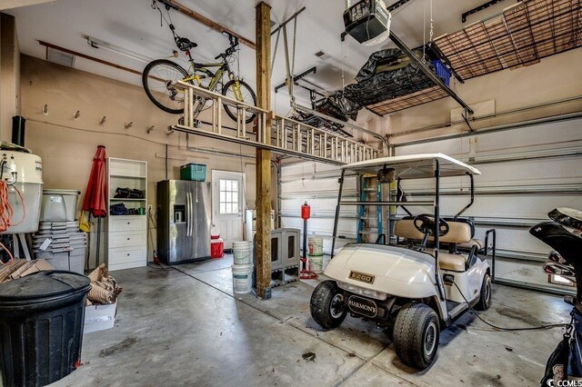 garage featuring a garage door opener and stainless steel refrigerator with ice dispenser